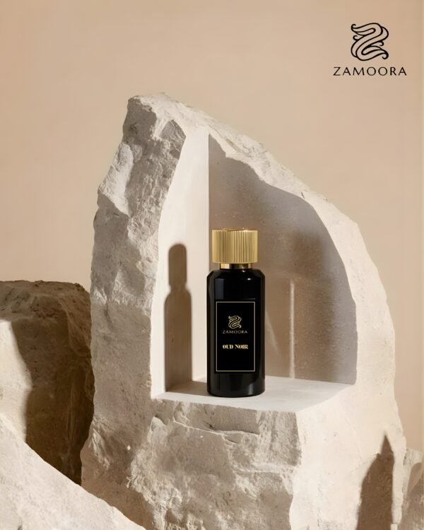 Zamoora Oud Noir perfume bottle for men placed on a wooden block in a smoky brown setting, showcasing top notes of blueberry and anise, heart notes of cashmere wood, floral notes and rosemary, and base notes of amber, honey and musk.